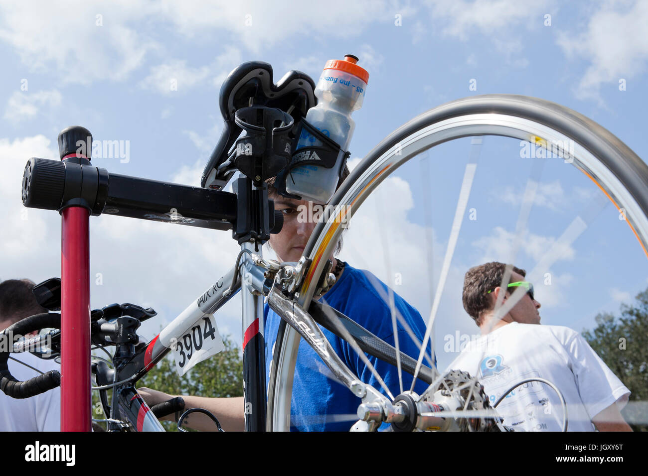 Bicycle mechanic fixing wheel with bicycle mounted on bike mount - USA Stock Photo