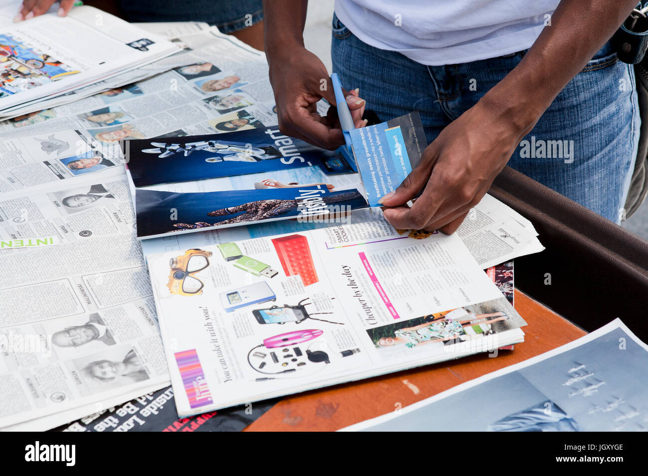 Black man clipping articles from a magazine using scissors - USA Stock Photo