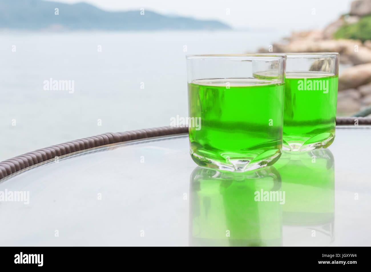 Two glasses of transparent green juice on the table near the sea. Stock Photo