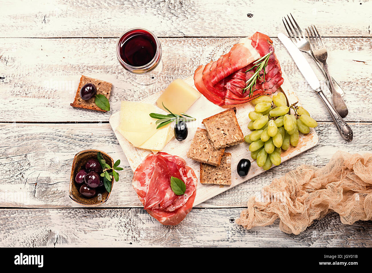 Typical italian antipasto, wooden cutting board with prosciutto, ham