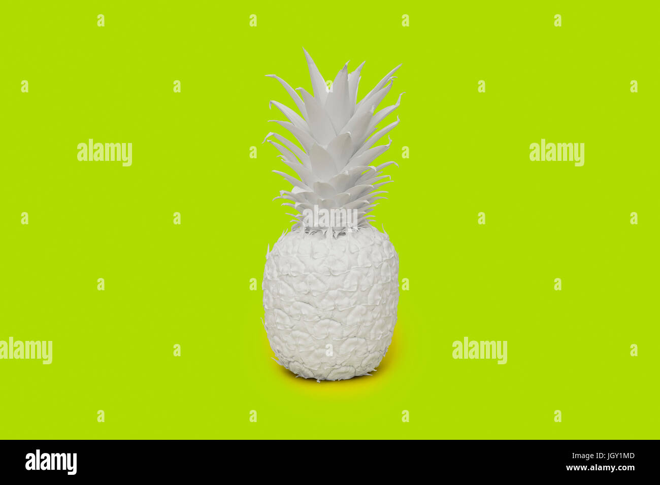 Pineapple painted white on lime green background Stock Photo