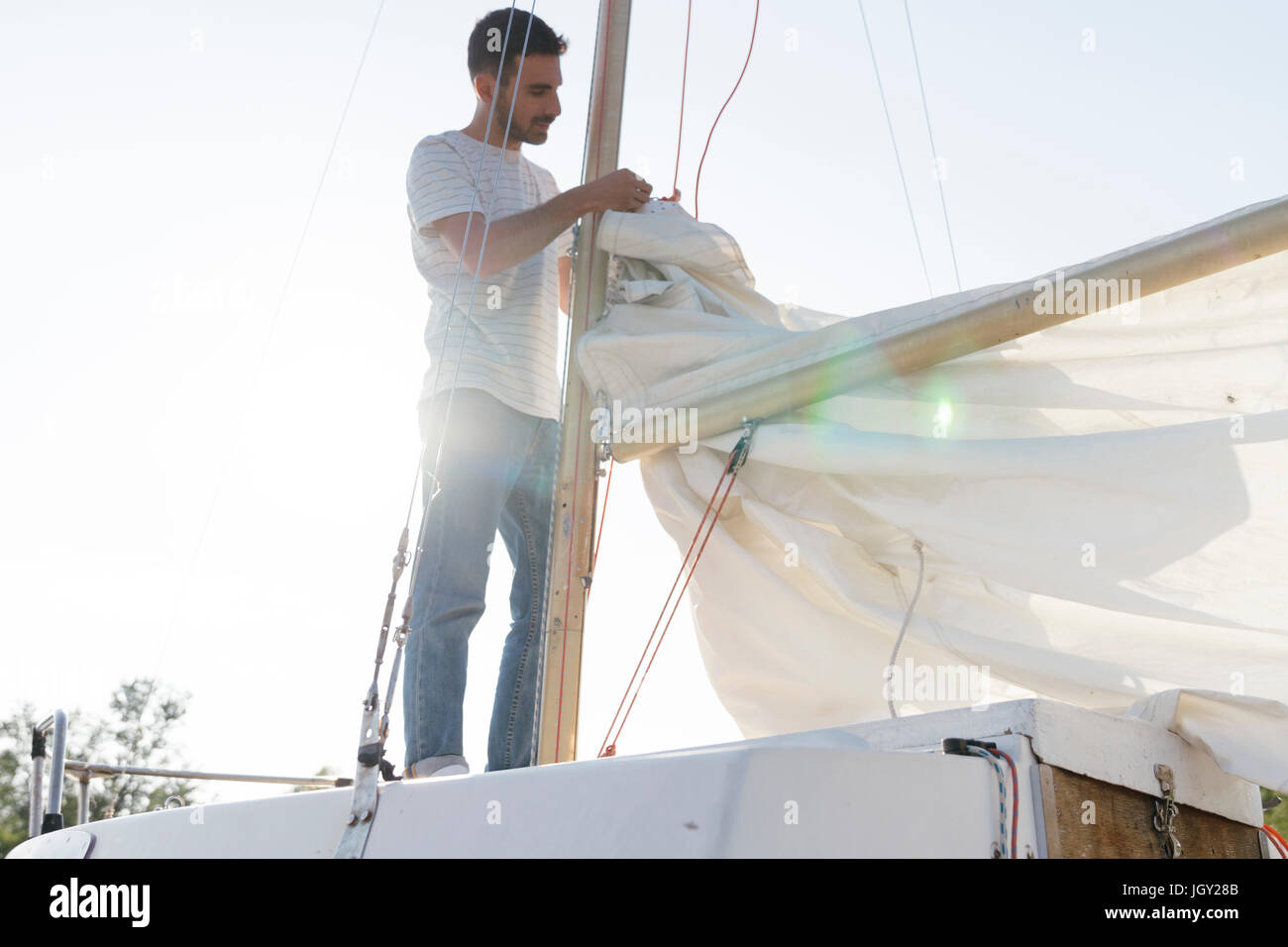 Man on sailing boat, preparing to hoist sail Stock Photo Alamy