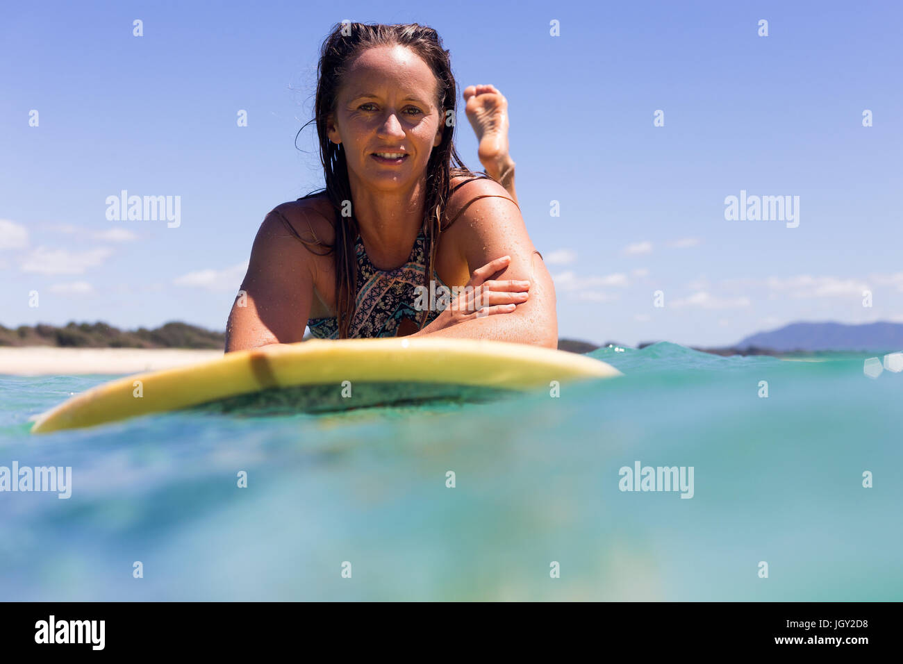A portrait of a happy young surfer girl in pristine tropical water on a clear summers day in Australia. Stock Photo