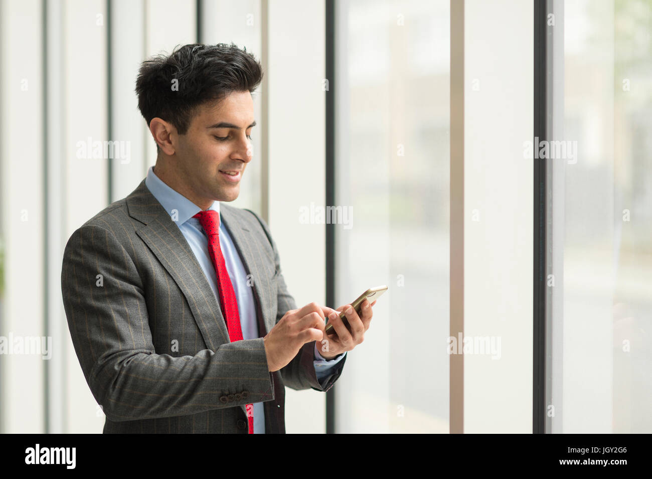 Businessman looking using smartphone touchscreen by office window Stock ...