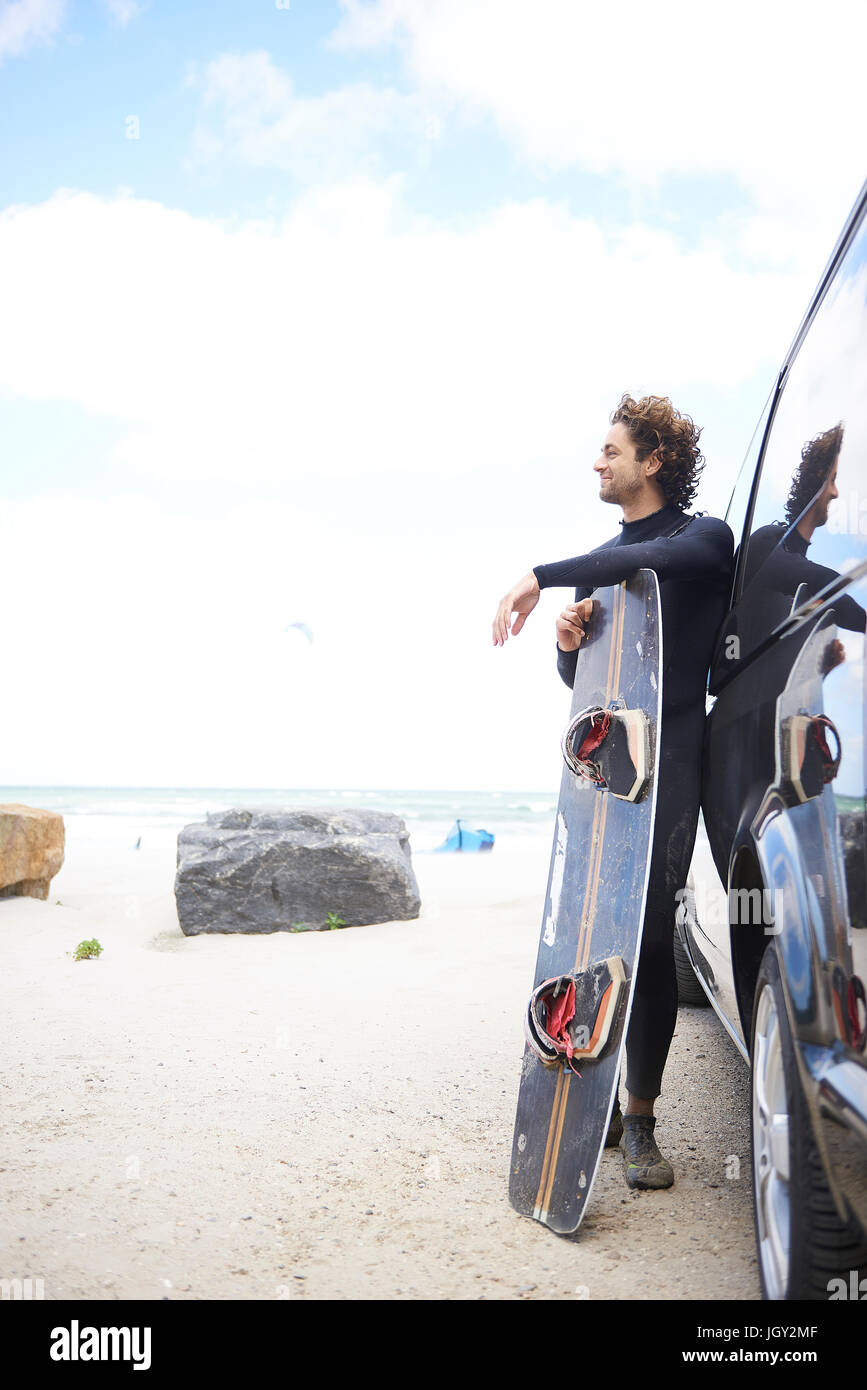 Kite surfer in wetsuit leaning against car, Hornbæk, Hovedstaden