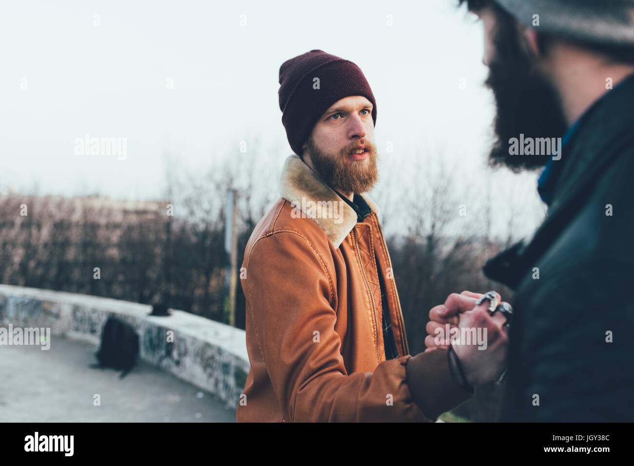 Two young male hipsters fist bumping in park Stock Photo