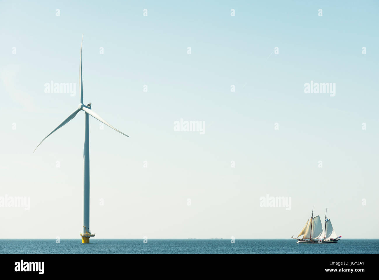 Off shore wind turbine and sailing ship on IJsselmeer lake, Netherlands Stock Photo