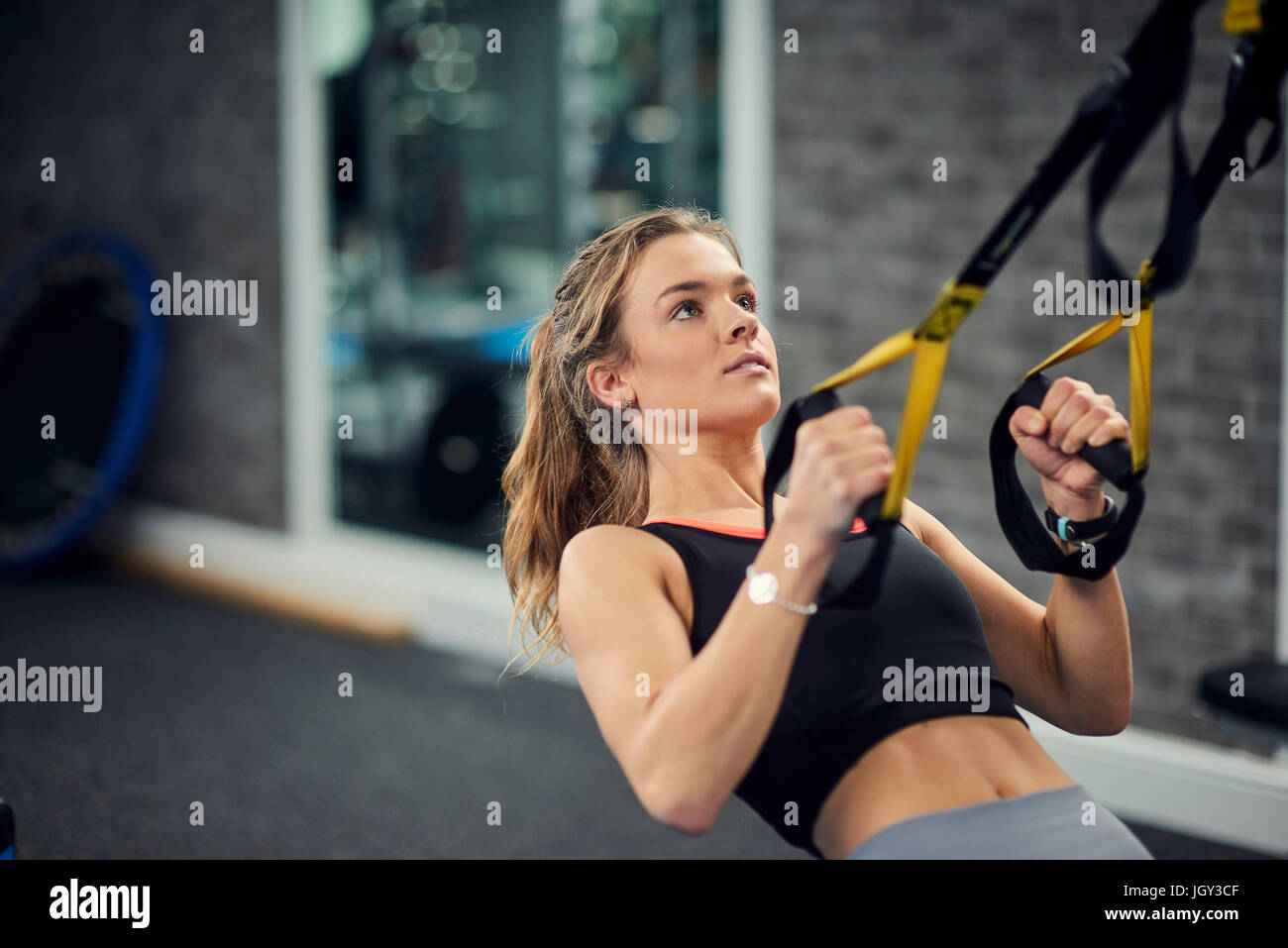 Young woman doing pull ups on exercise handles in gym Stock Photo