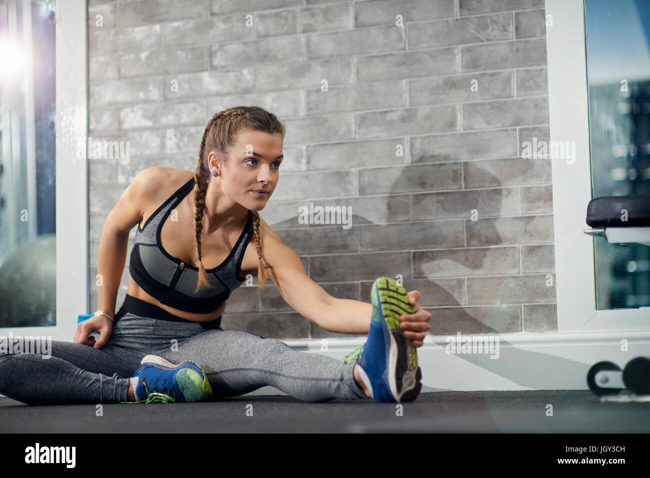 Young woman training, touching toes in gym Stock Photo