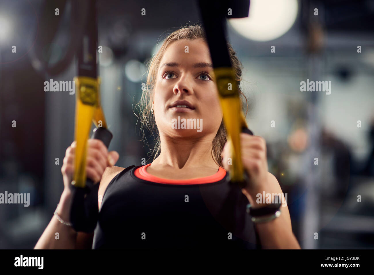 Young woman doing pull ups on exercise handles in gym Stock Photo