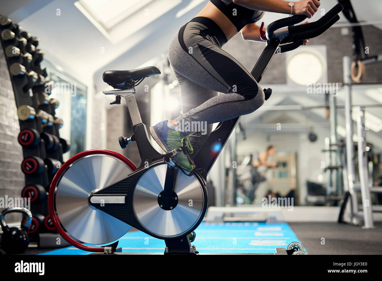 Neck down view of young woman training, pedalling exercise bike in gym Stock Photo