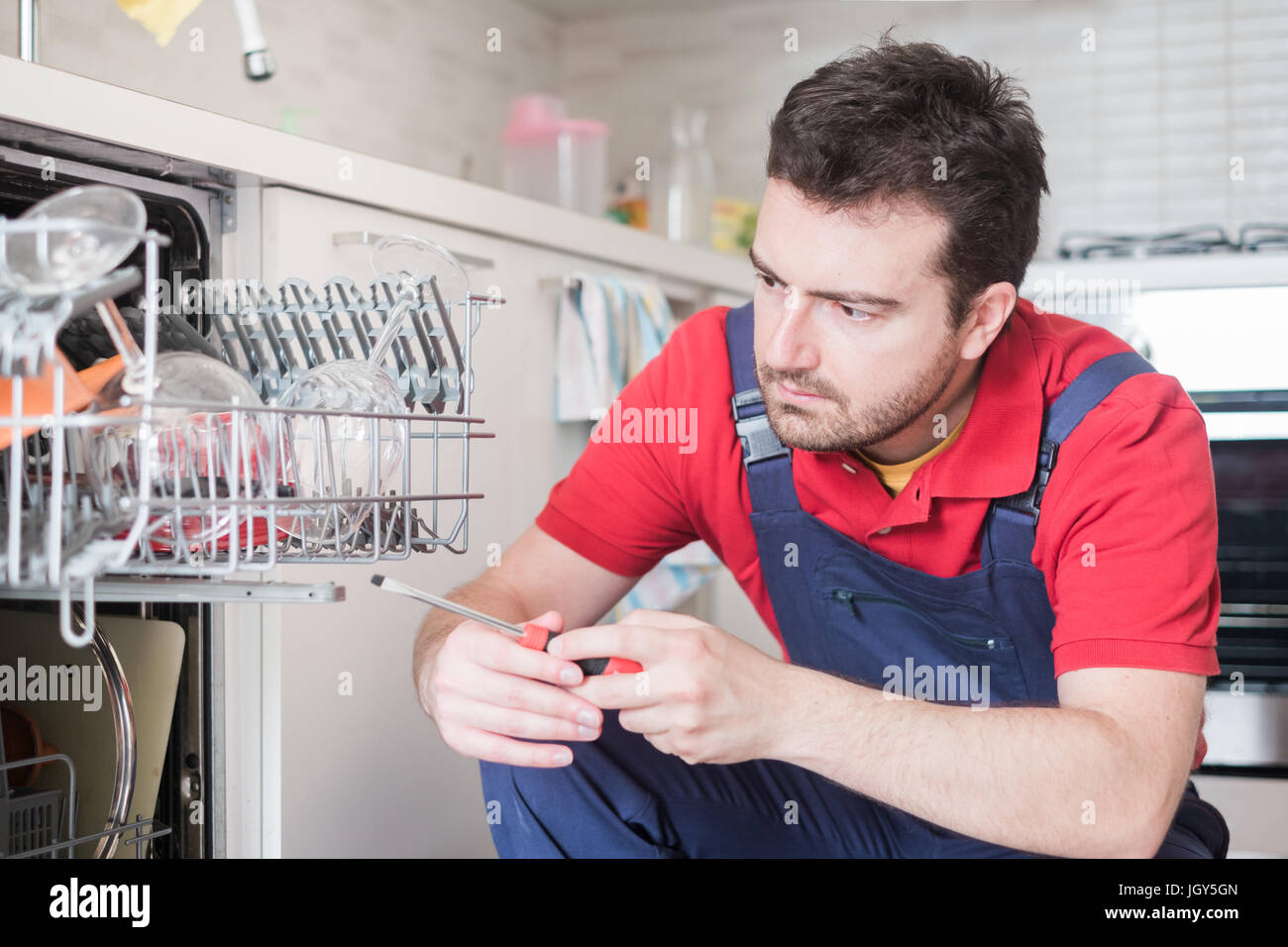 Professional Worker Repairing The Dishwasher In Kitchen Professional Worker Repairing The Dishwasher In Kitchen