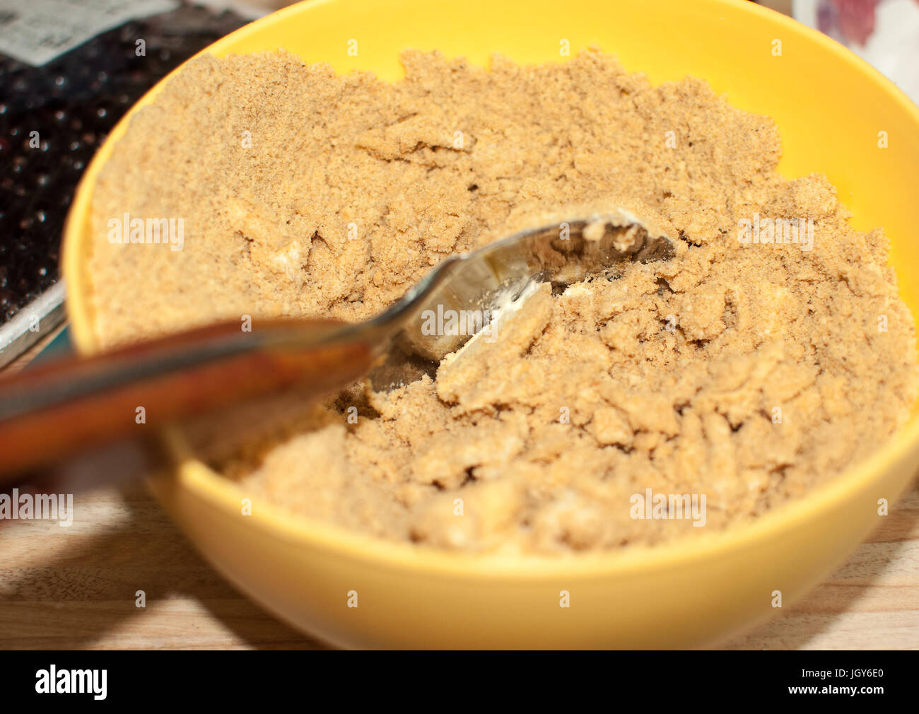 Biscuit crumbs and butter in yellow bowl close up. Process of cooking