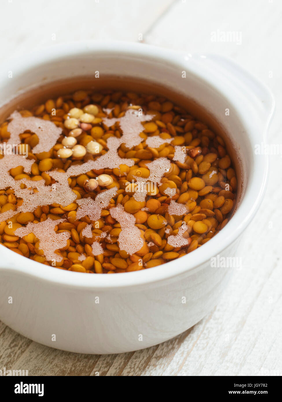 Lentils soaking in water to make them easier to digest Stock Photo