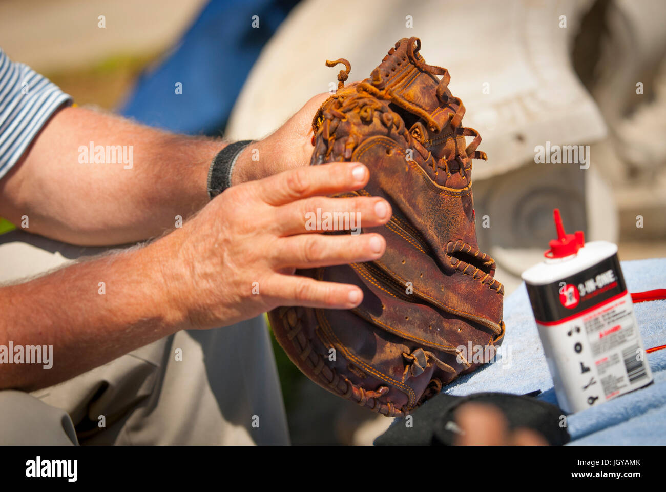 A baseball player oils his glove to soften it and make it more pliable