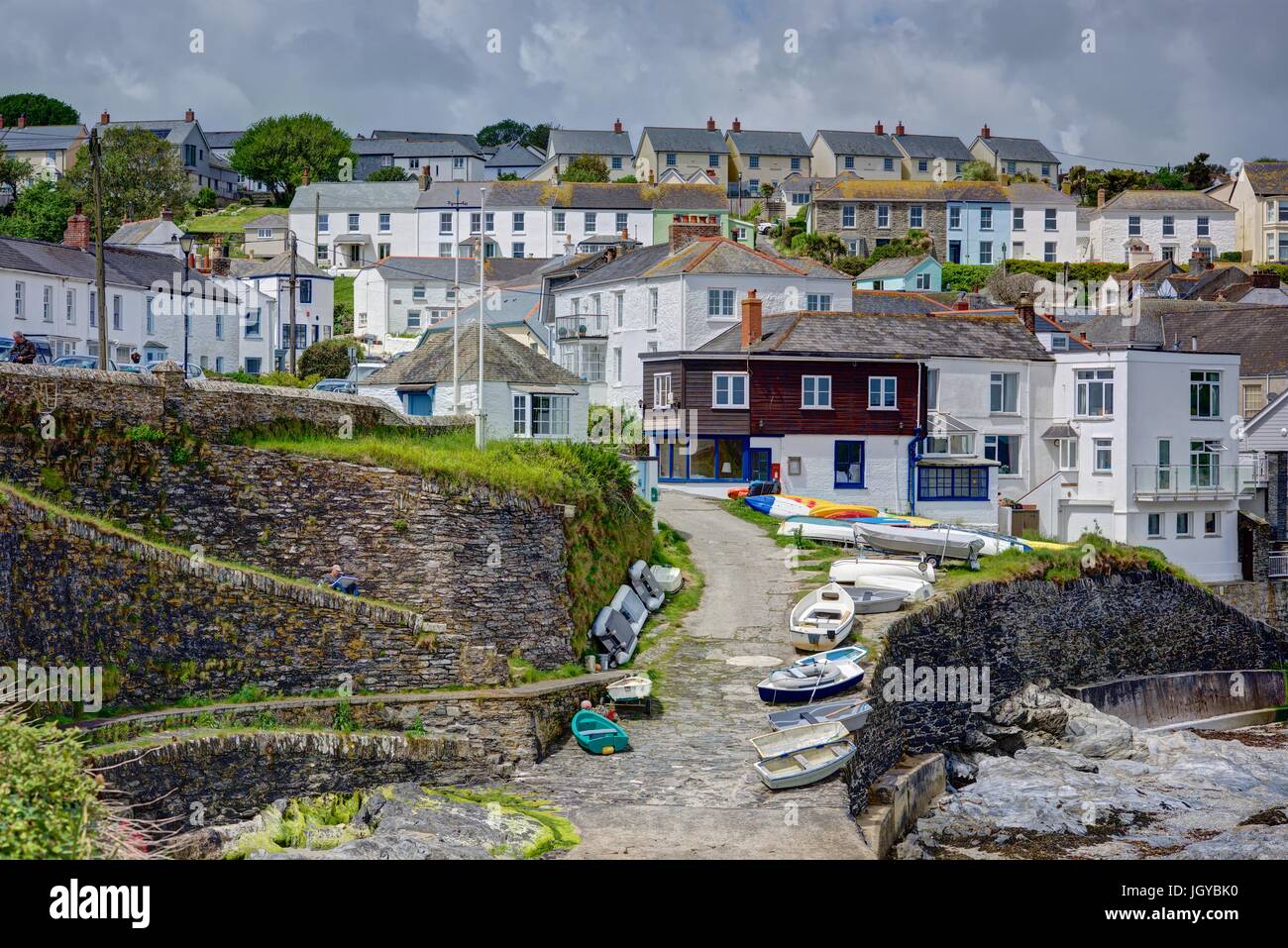 A colourful bright sunny image of Portscatho, Cornwall, showing the harbour sea defences and moored boats with the village cottages in the background Stock Photo