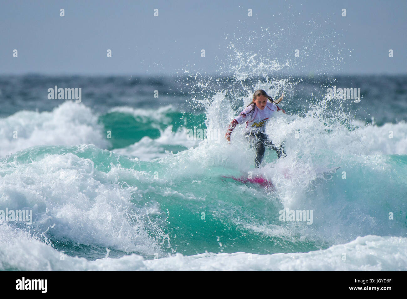 Surfing UK. Surfing child wave.  A young female surfer competing in the UK Schools Surf Championship. Stock Photo