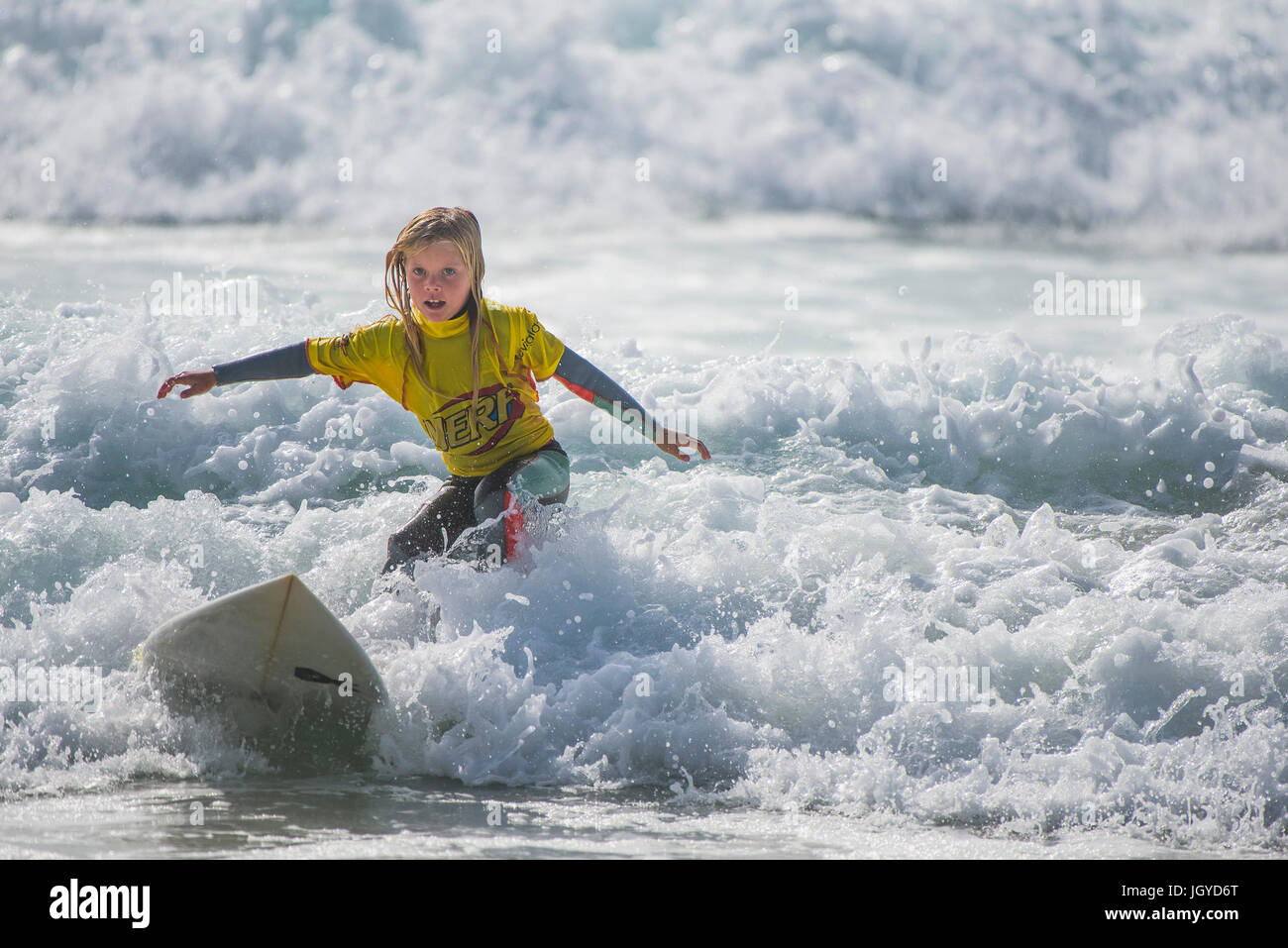 Surfing UK. Surfing child wave. An eight year old surfer competing in the UK Schools Surf Championship. Stock Photo