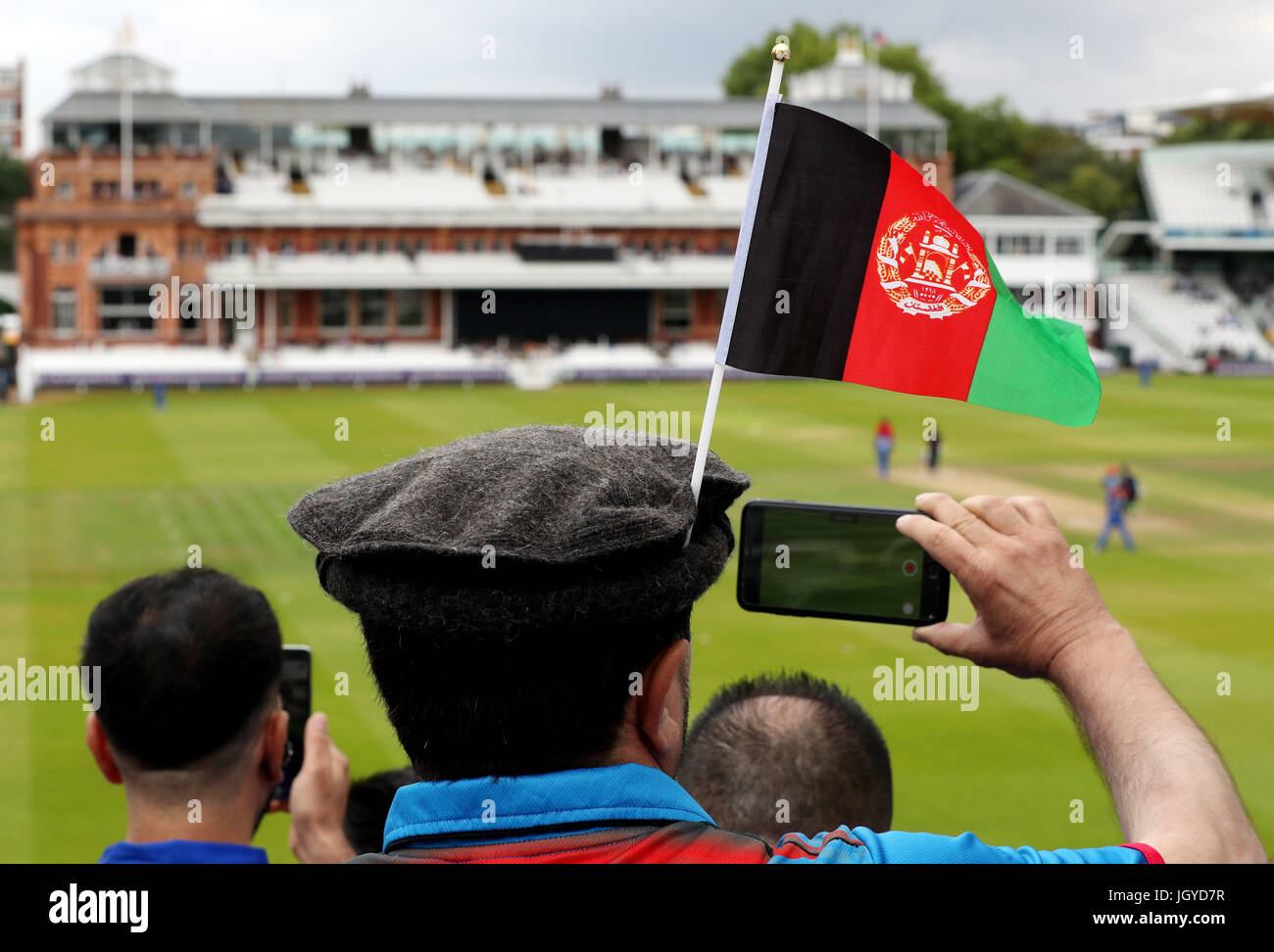 An Afghanistan cricket fan wears his national flag in his hat with the pavilion in the distance during the one day match between MCC and Afghanistan at Lord's, London. Stock Photo