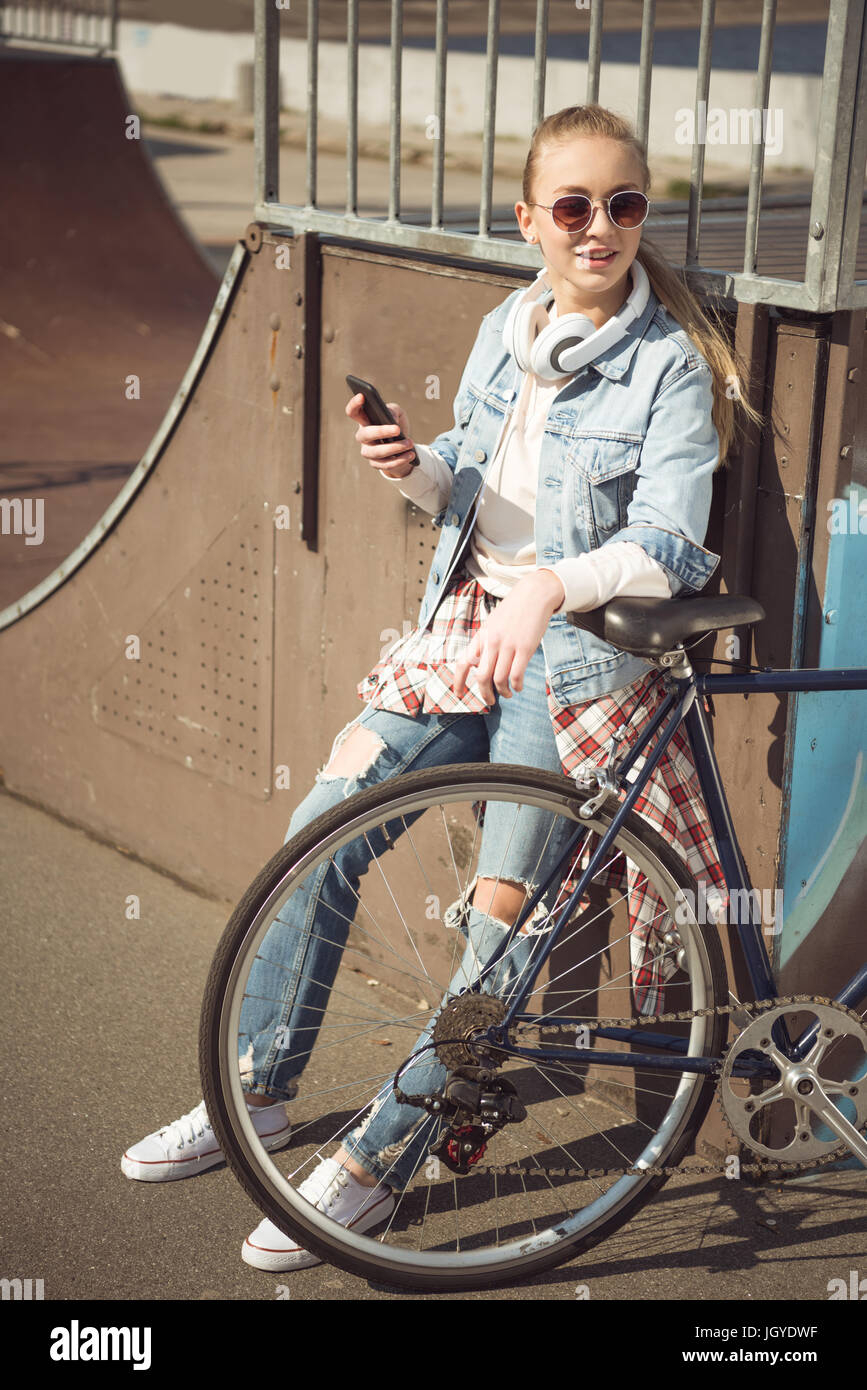 Stylish young blonde girl in sunglasses standing with bmx bike and