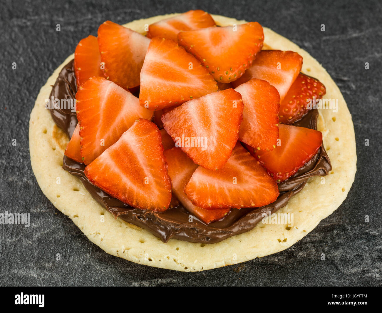 Pancake With Strawberries and Chocolate Spread Against A Black Background Stock Photo