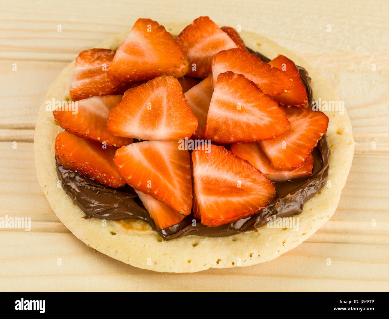 Pancake With Strawberries and Chocolate Spread Against A Pinewood Background Stock Photo