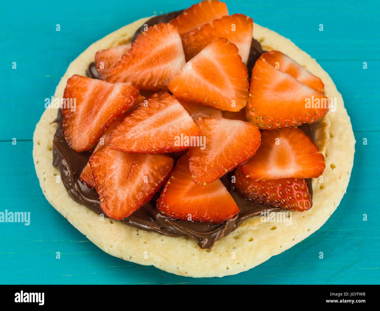 Pancake With Strawberries and Chocolate Spread Against A Blue Background Stock Photo