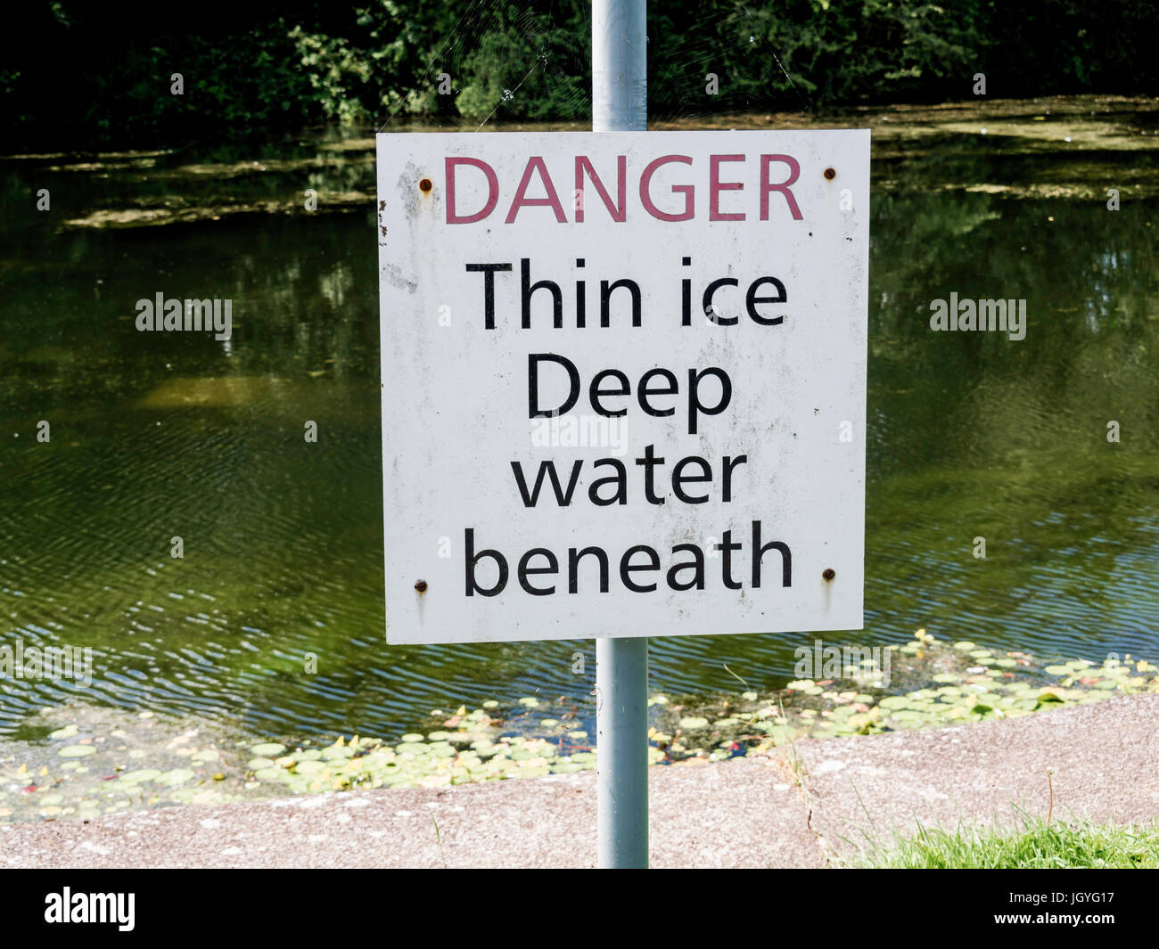 Sign on a canal bank  Danger Thin Ice Deep Water Beneath Stock Photo