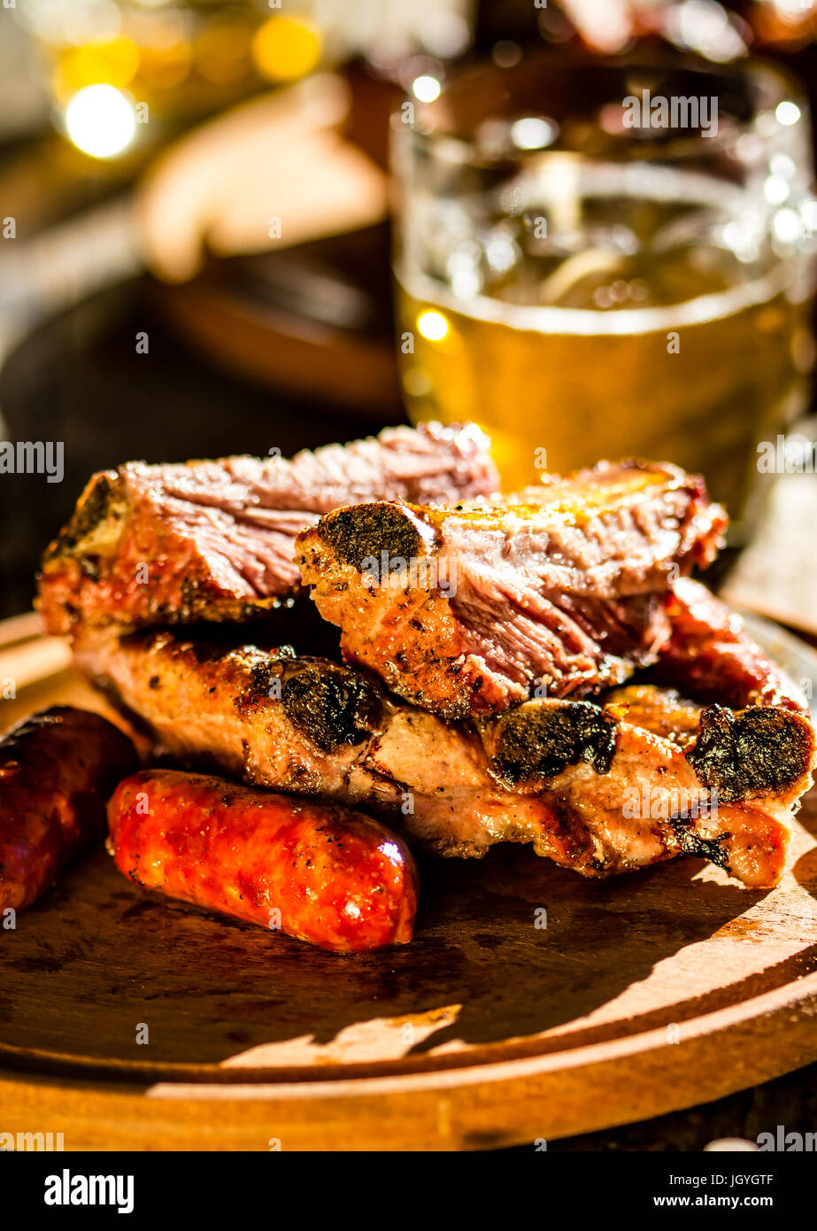 Barbecue pork ribs and sausages with beer on wooden board Stock Photo