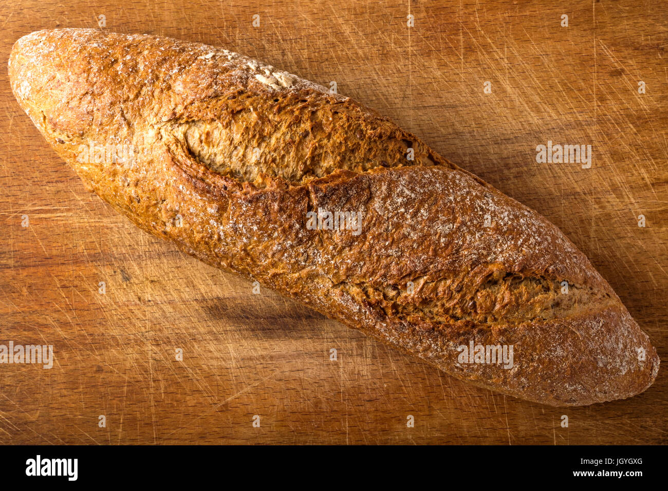 Brown baguette with different seeds, such as sesame and poppy, on wooden background Stock Photo
