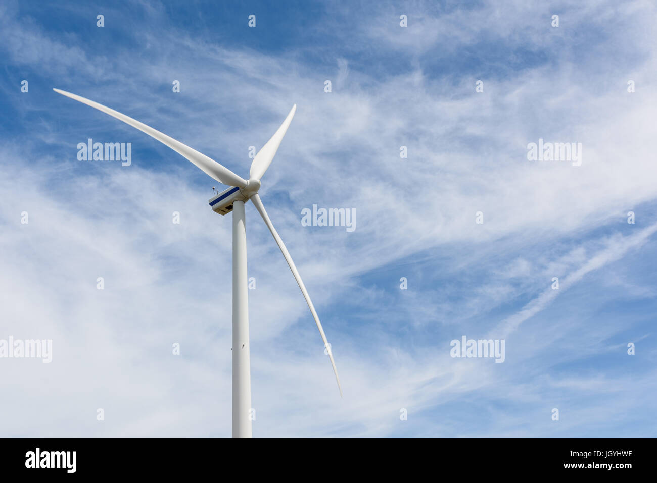 Close up of a wind turbine on a sunny day against a blue clouded sky ...
