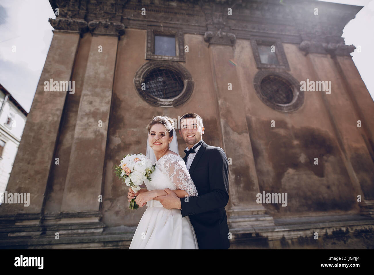 bride and groom standing near the old brown house Stock Photo - Alamy
