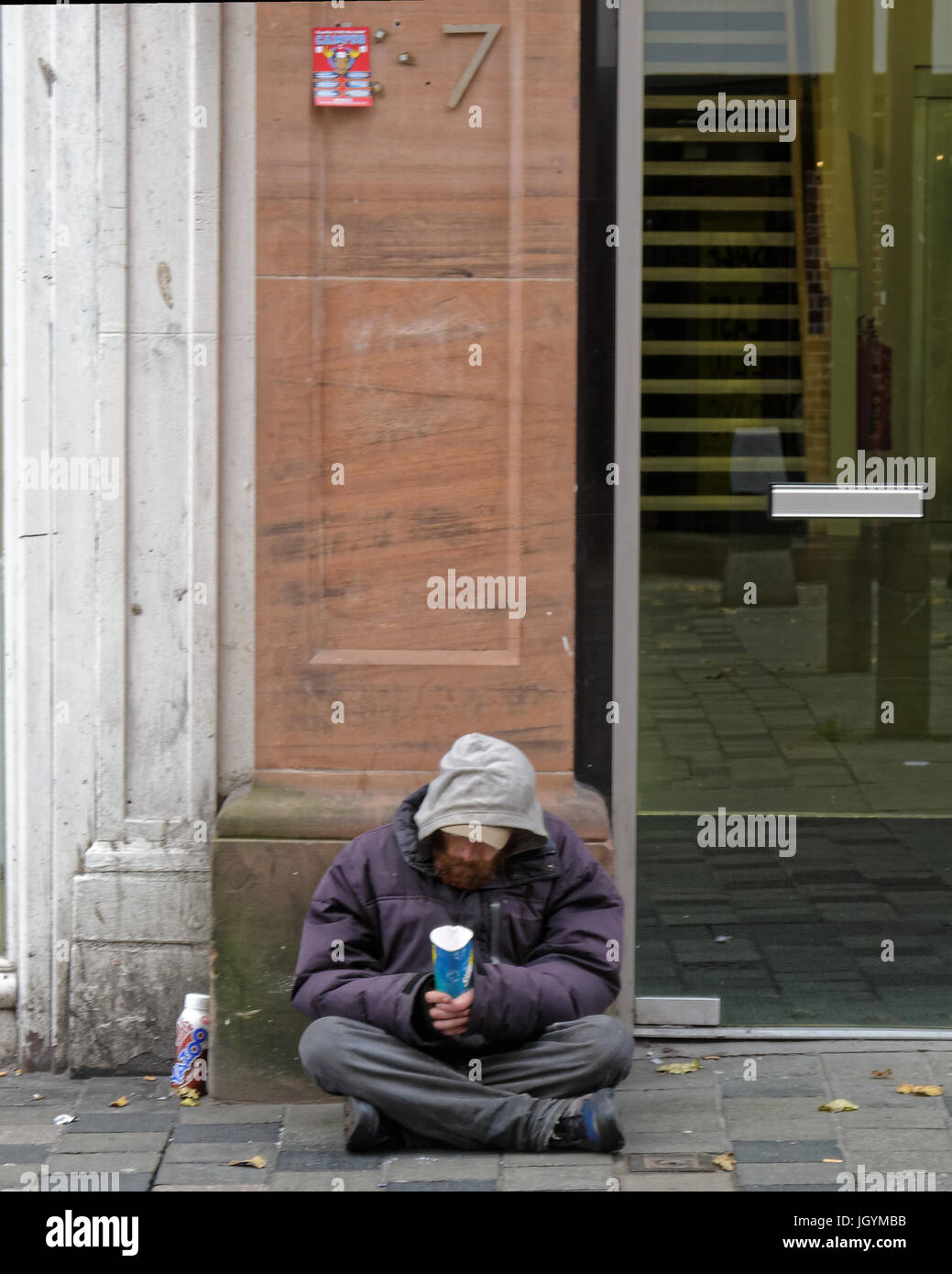 begging homeless unemployed man begging  on the street with cup no people walking by Stock Photo