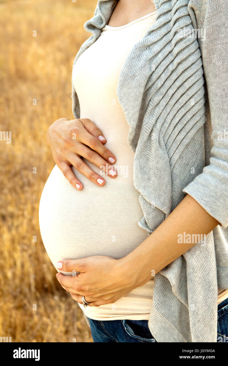 Young pregnant woman ouside holding her belly Stock Photo - Alamy