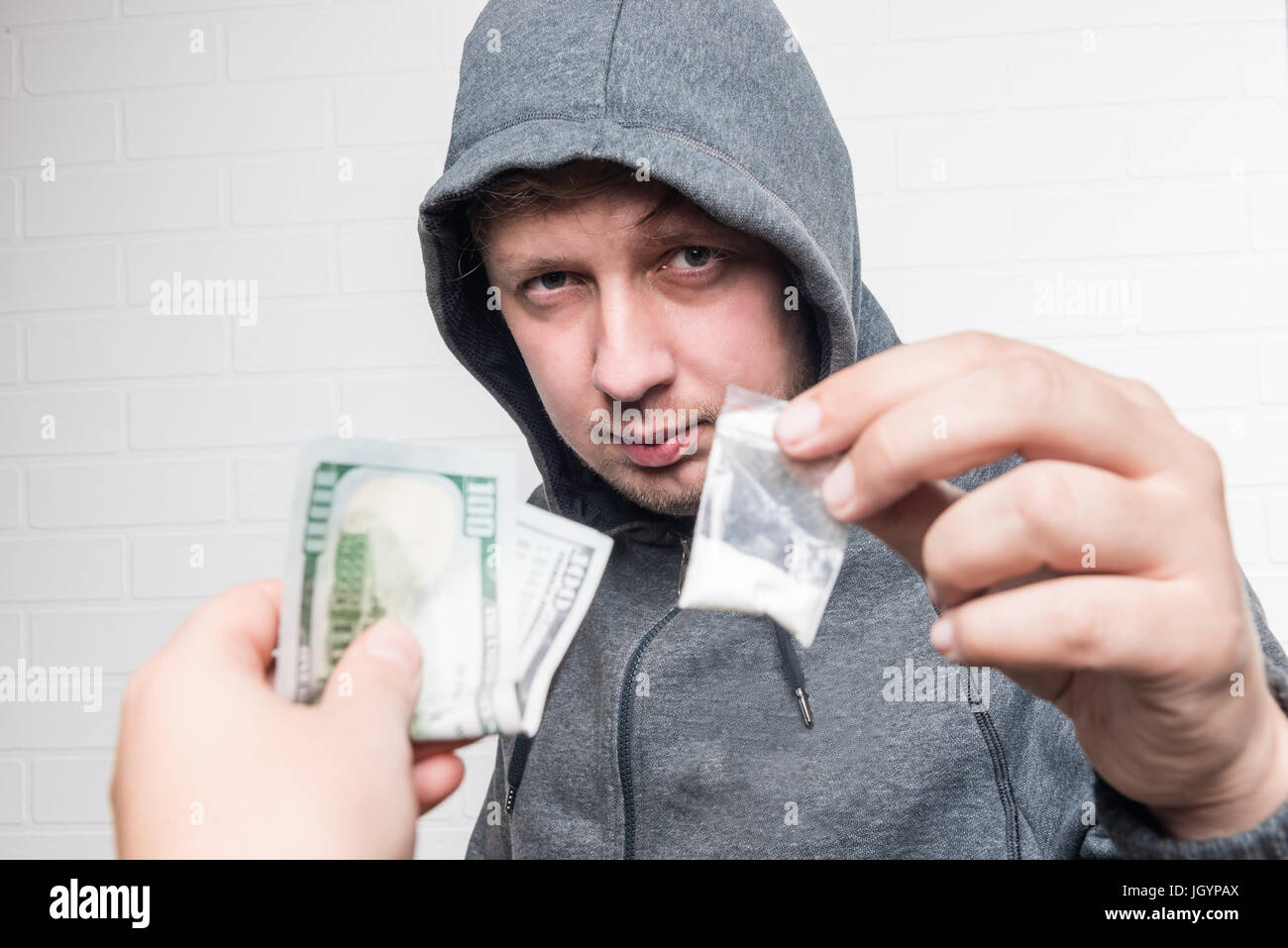 Portrait of a drug dealer with drugs and a female hand with money Stock Photo