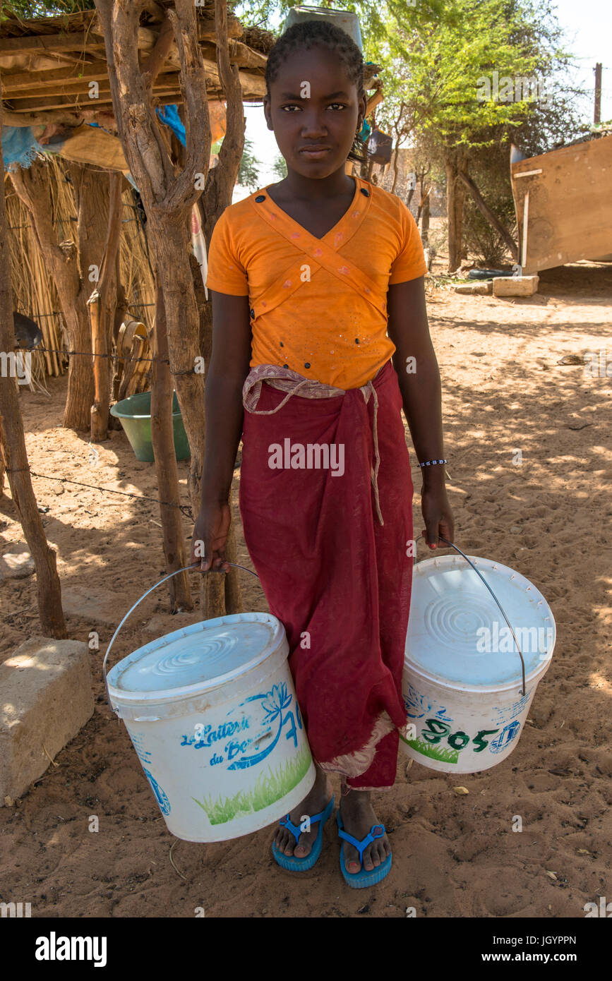 Peul girl carrying buckets of milk. Senegal. Stock Photo