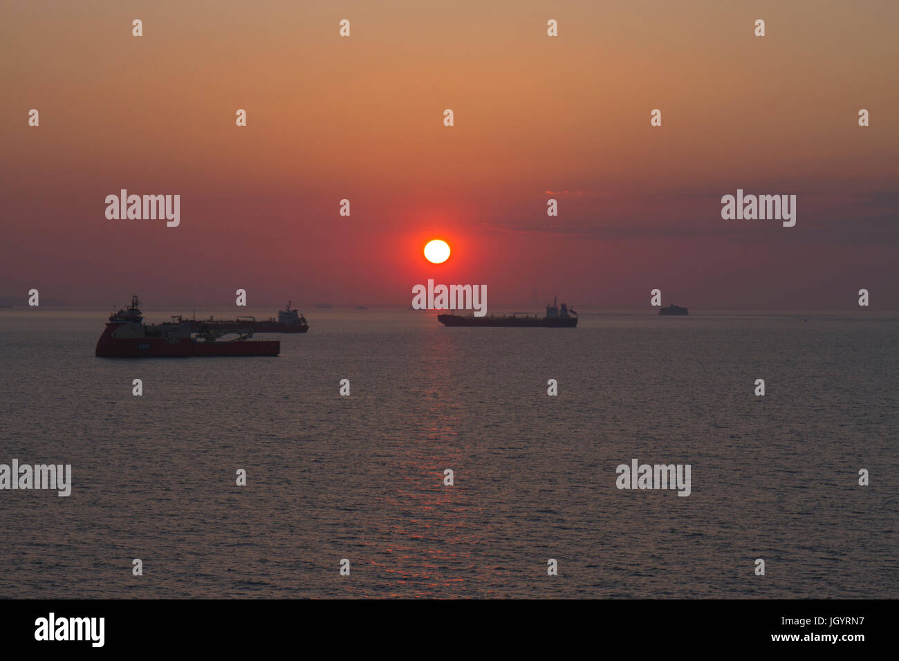 Sunset over Solent and  oil tankers. Taken from a ferry heading to Portsmouth, Hampshire, England. May. Stock Photo