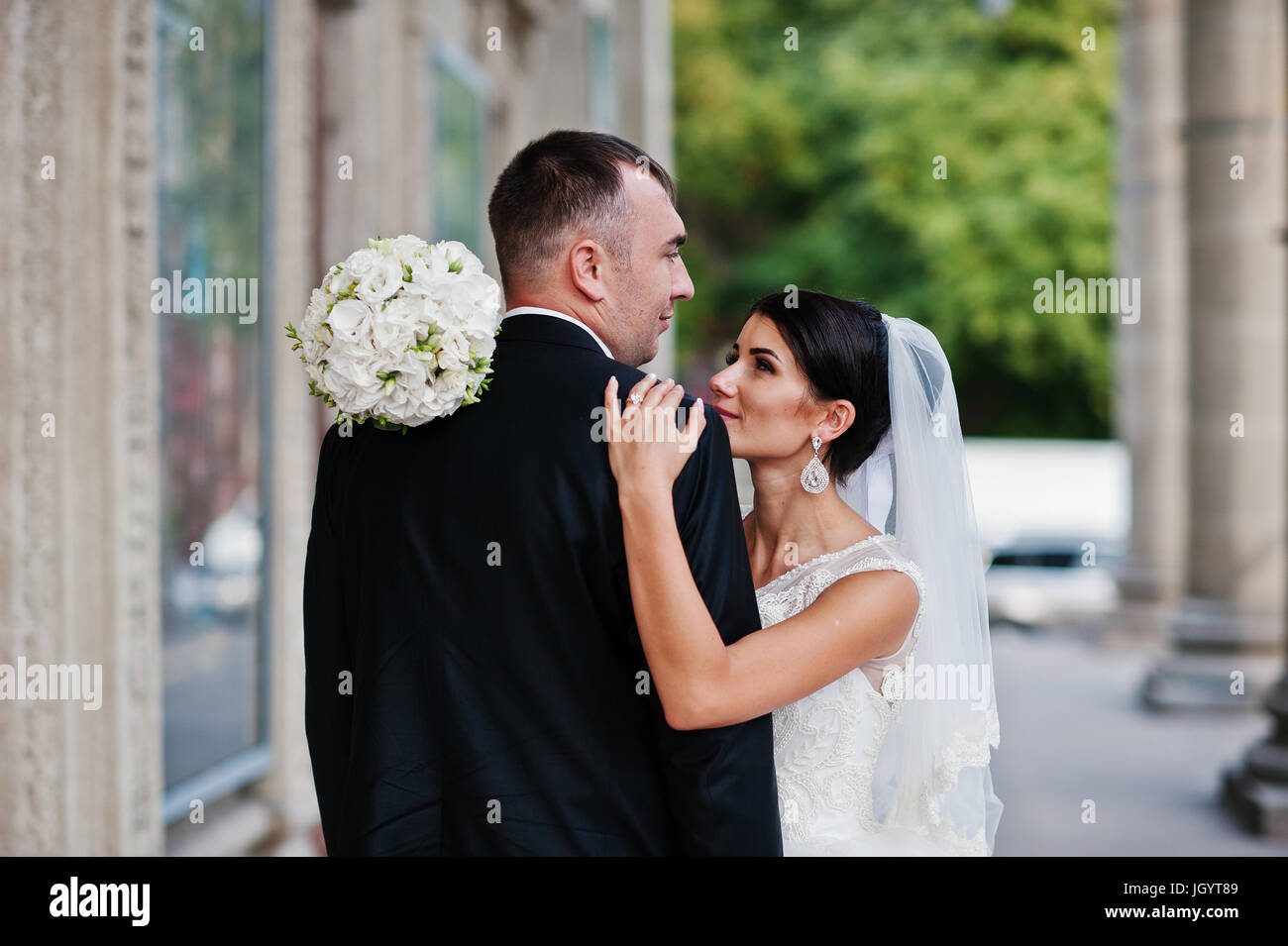Fabulous wedding couple walking and posing next to the columns on a ...