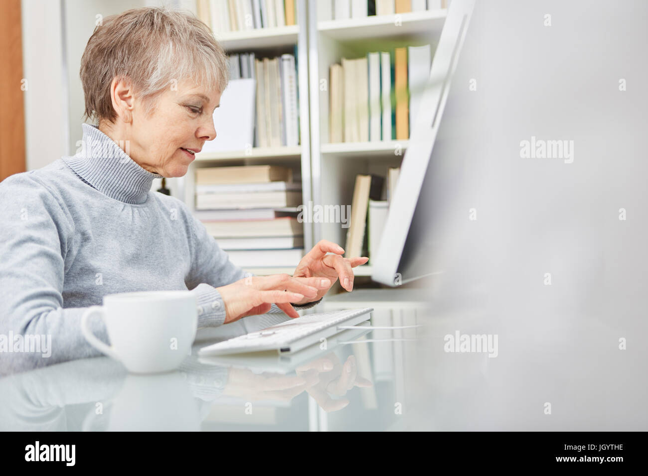 Senior woman surfing the internet with computer at home office Stock Photo