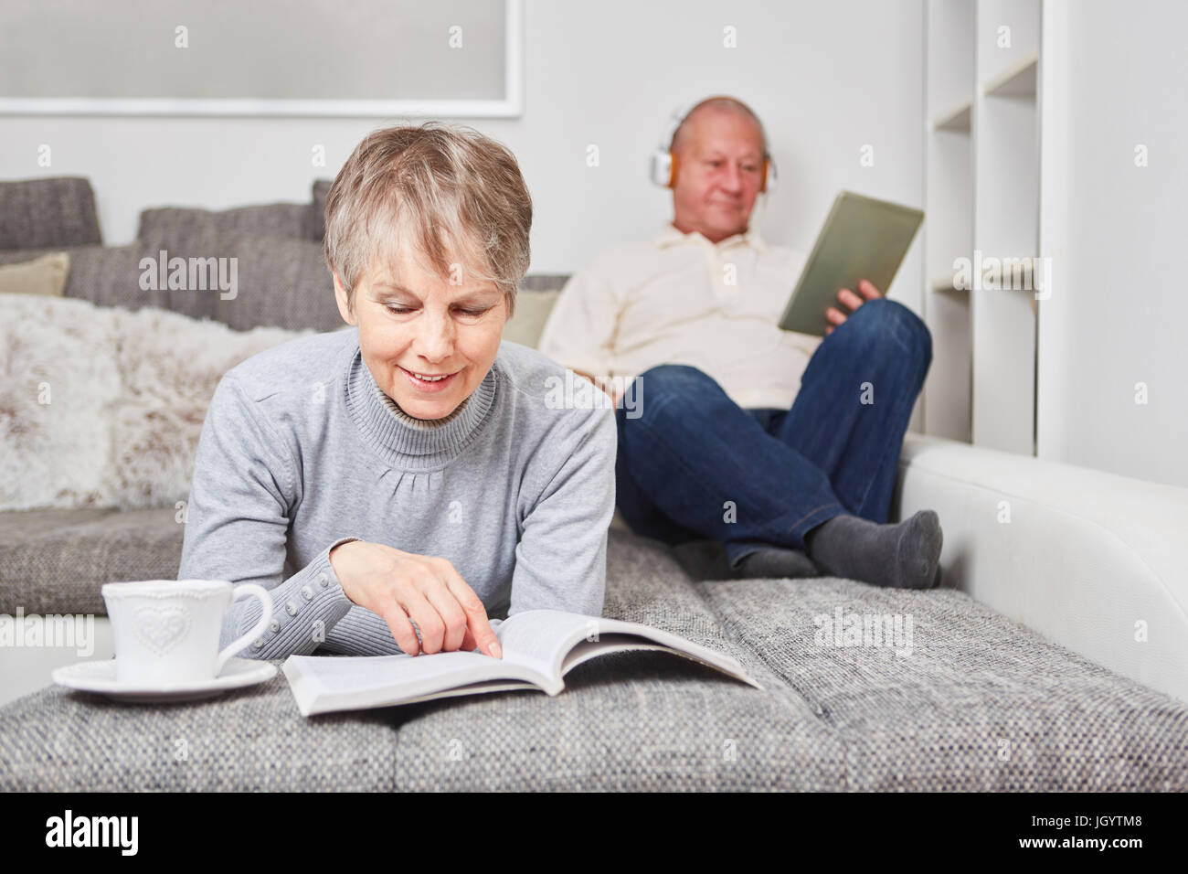 Woman as senior with a book on the couch for relaxation Stock Photo