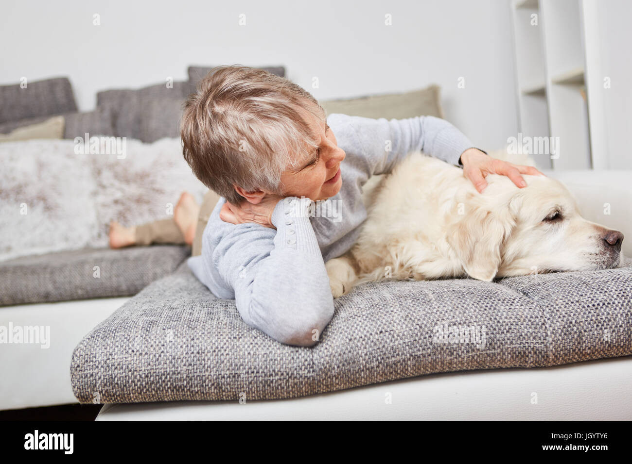Senior woman with dog Retriever on the couch for relaxation Stock Photo