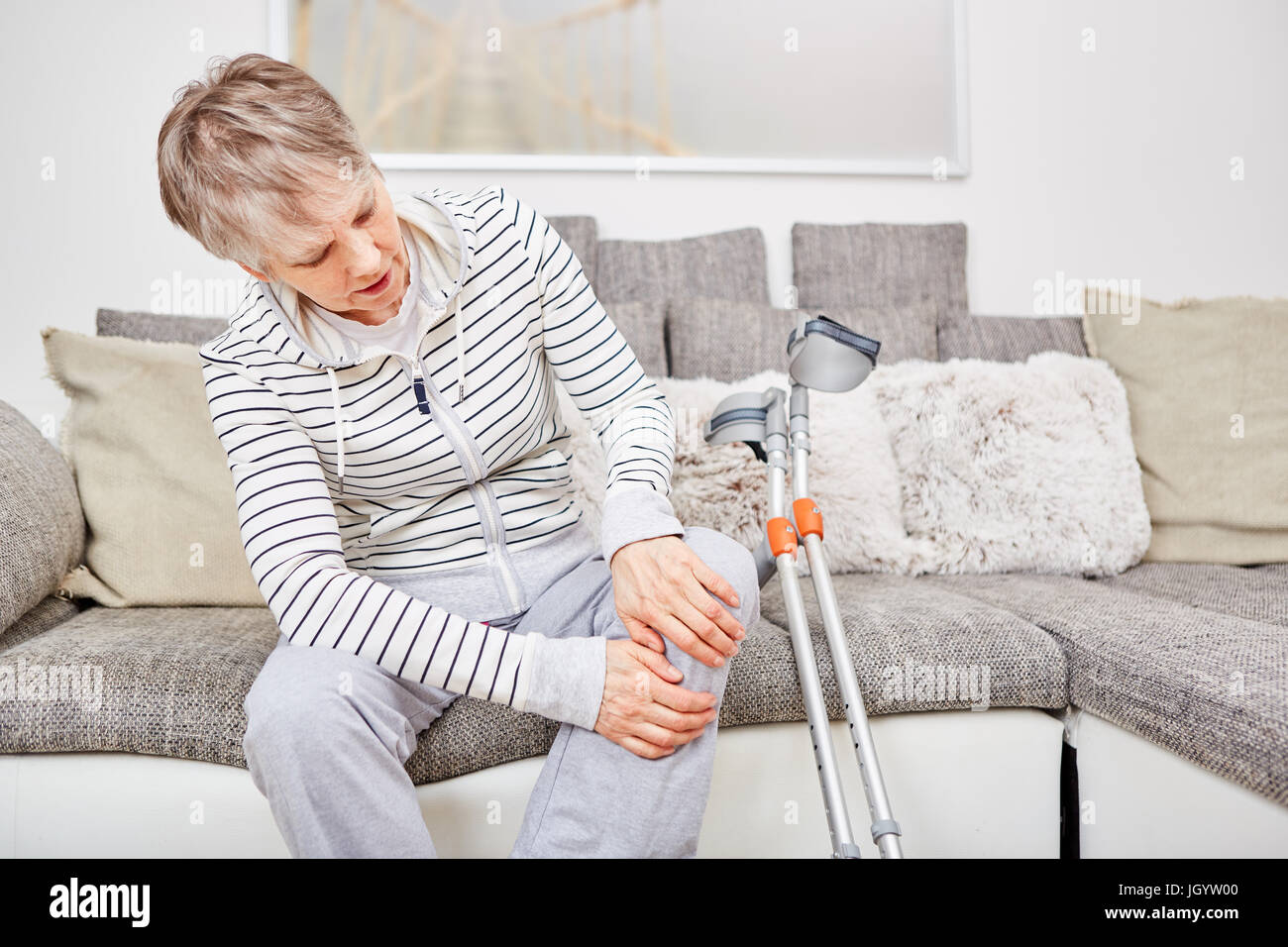 Senior woman with crutches and knee injury has pain Stock Photo Alamy