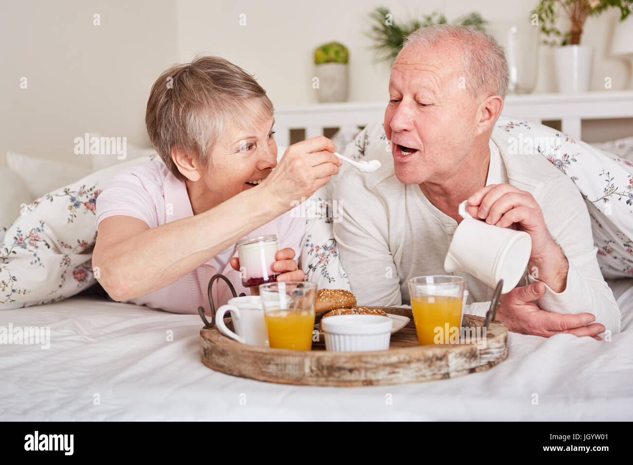 Happy seniors having breakfast in bed together in romanctic pension Stock Photo