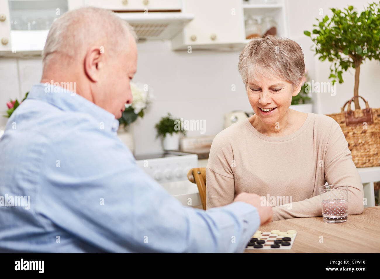 Seniors play board game for leisure and relaxation as couple in retirement activity Stock Photo