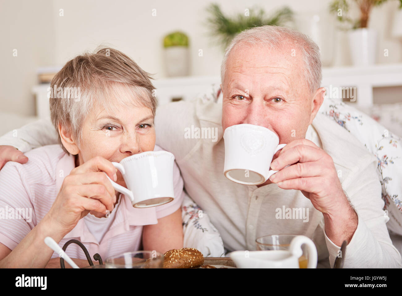 Seniors drinking coffee in bed in romantic hotel Stock Photo Alamy