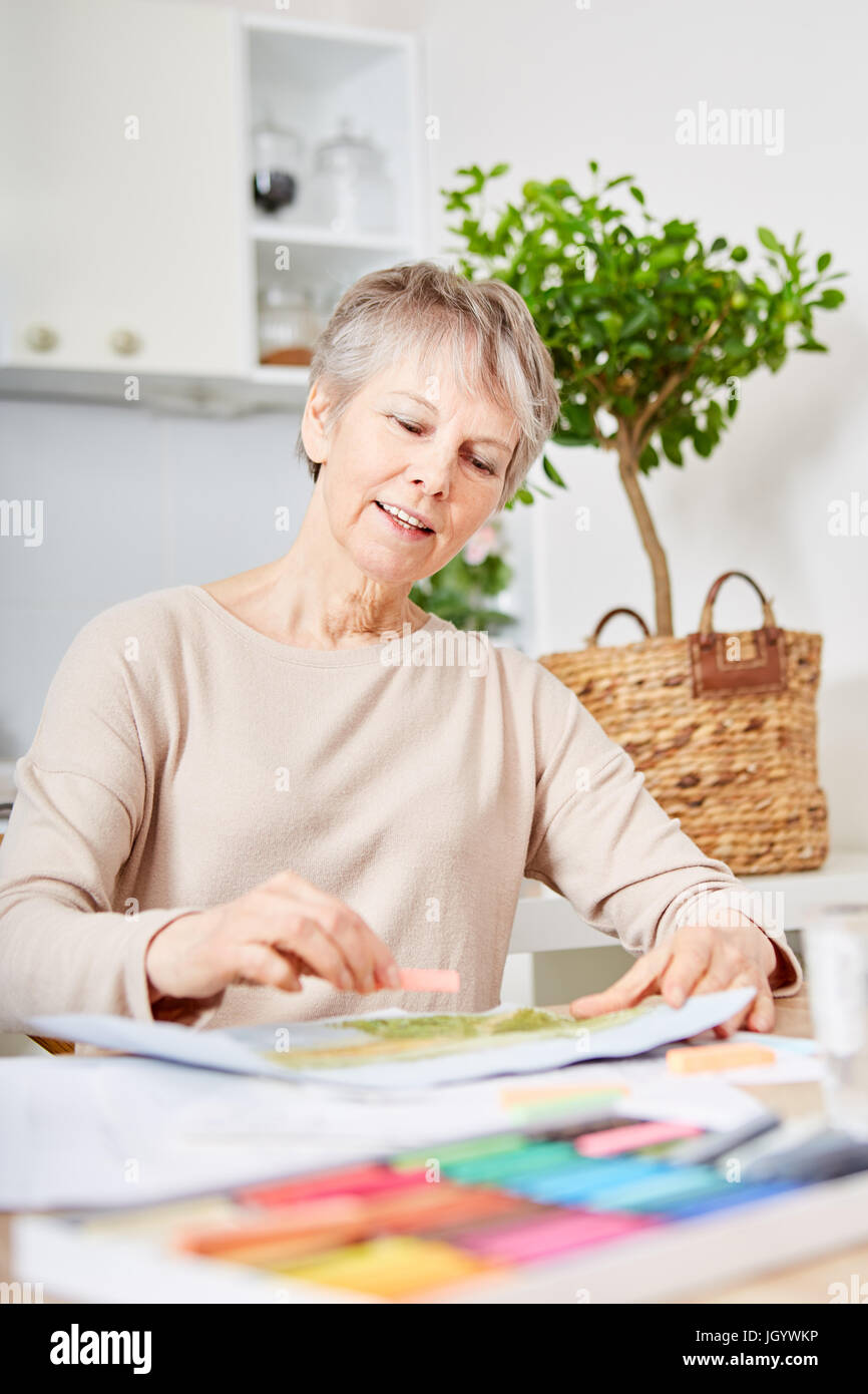 Senior woman with dementia painting at home as Alyheimer's therapy