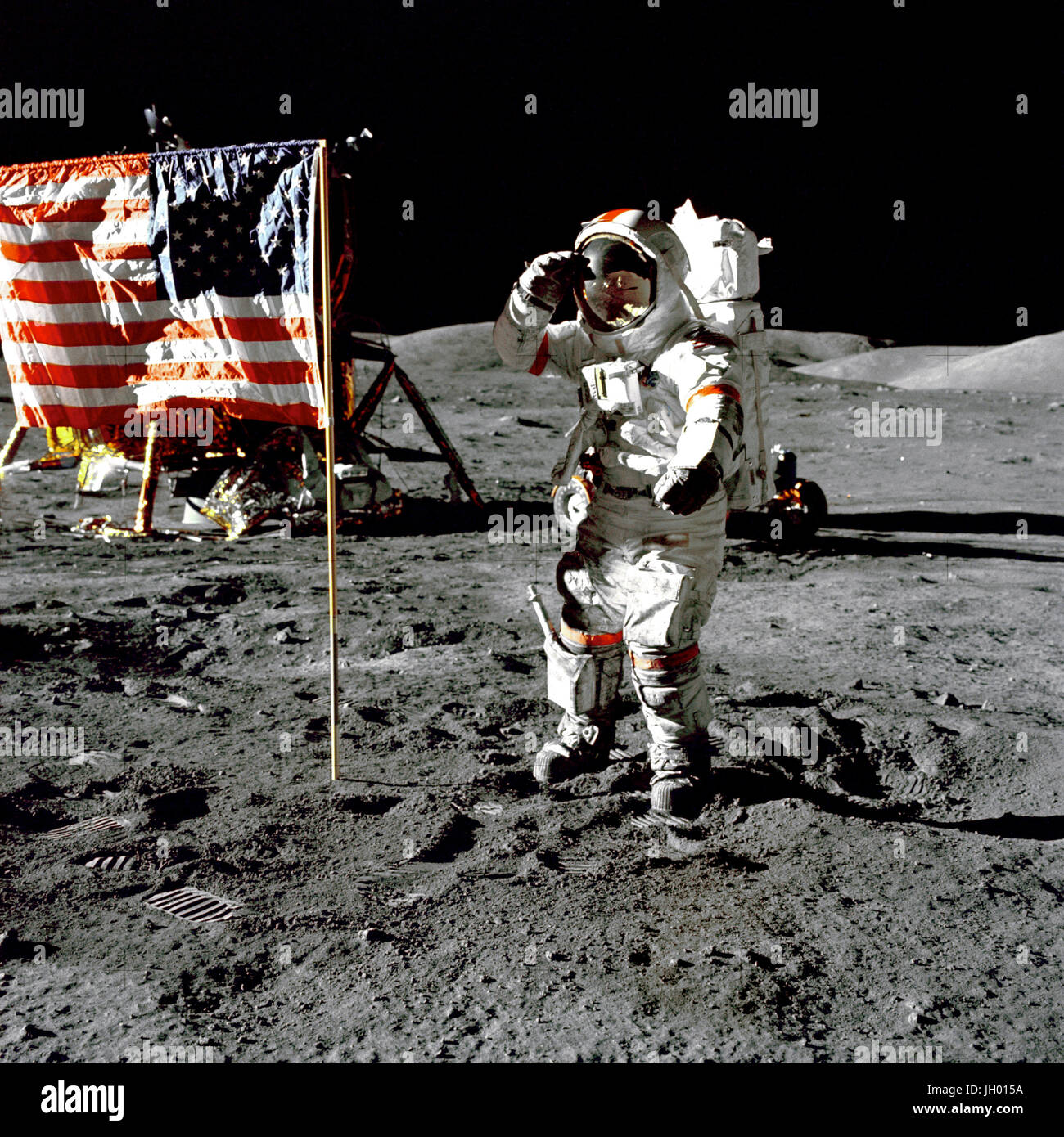 Cernan Jump Salutes Flag. Eugene A. Cernan, Commander, Apollo 17 salutes the flag on the lunar surface during extravehicular activity (EVA) on NASA's final lunar landing mission. The Lunar Module 'Challenger' is in the left background behind the flag and the Lunar Roving Vehicle (LRV) also in background behind him. While astronauts Cernan and Schmitt descended in the Challenger to explore the Taurus-Littrow region of the Moon, astronaut Ronald E. Evans, Command Module pilot, remained with the Command/Service Module (CSM) 'America' in lunar-orbit. Photographer: NASA Harrison Schmitt Stock Photo