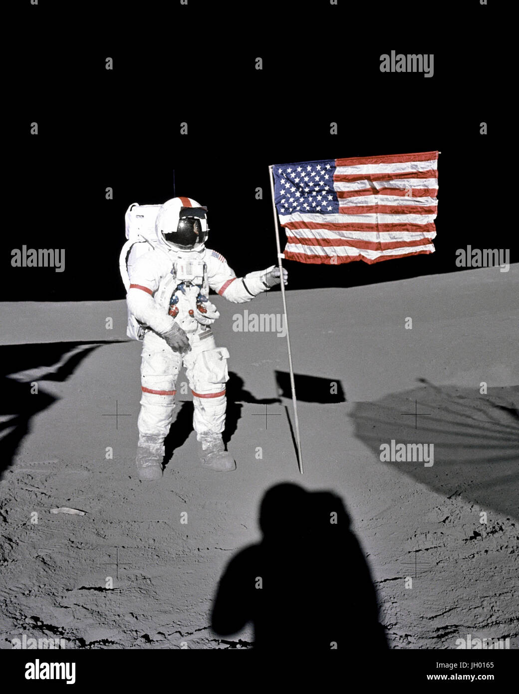 Astronaut Alan B. Shepard Jr., Apollo 14 Commander, stands by the U.S. flag on the lunar Fra Mauro Highlands during the early moments of the first extravehicular activity (EVA-1) of the mission. Shadows of the Lunar Module 'Antares', astronaut Edgar D. Mitchell, Lunar Module pilot, and the erectable S-band Antenna surround the scene of the third American flag planting to be performed on the lunar surface. Stock Photo