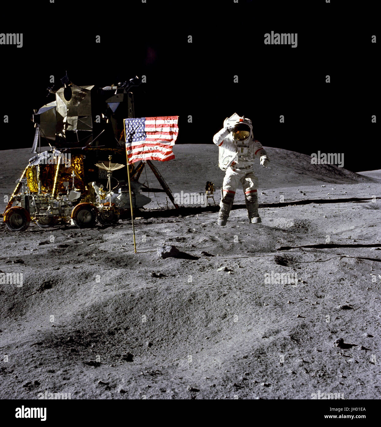 Young. Astronaut John W. Young, commander of the Apollo 16 lunar landing mission, jumps up from the lunar surface as he salutes the U.S. Flag at the Descartes landing site during the first Apollo 16 extravehicular activity (EVA-1). Astronaut Charles M. Duke Jr., lunar module pilot, took this picture. The Lunar Module (LM) 'Orion' is on the left. The Lunar Roving Vehicle is parked beside the LM. The object behind Young in the shade of the LM is the Far Ultraviolet Camera/Spectrograph. Stone Mountain dominates the background in this lunar scene. Photographer: NASA /Charles M. Duke Jr. Stock Photo