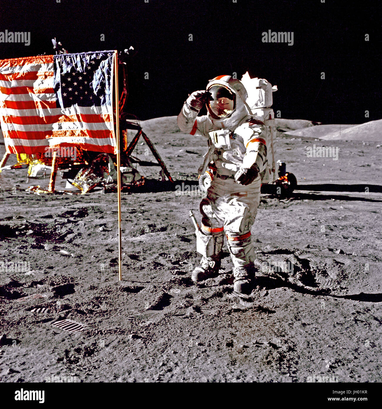 Eugene A. Cernan, Commander, Apollo 17 salutes the flag on the lunar surface during extravehicular activity (EVA) on NASA's final lunar landing mission. The Lunar Module 'Challenger' is in the left background behind the flag and the Lunar Roving Vehicle (LRV) also in background behind him. While astronauts Cernan and Schmitt descended in the Challenger to explore the Taurus-Littrow region of the Moon, astronaut Ronald E. Evans, Command Module pilot, remained with the Command/Service Module (CSM) 'America' in lunar-orbit. Photographer: NASA / Harrison Schmitt Stock Photo